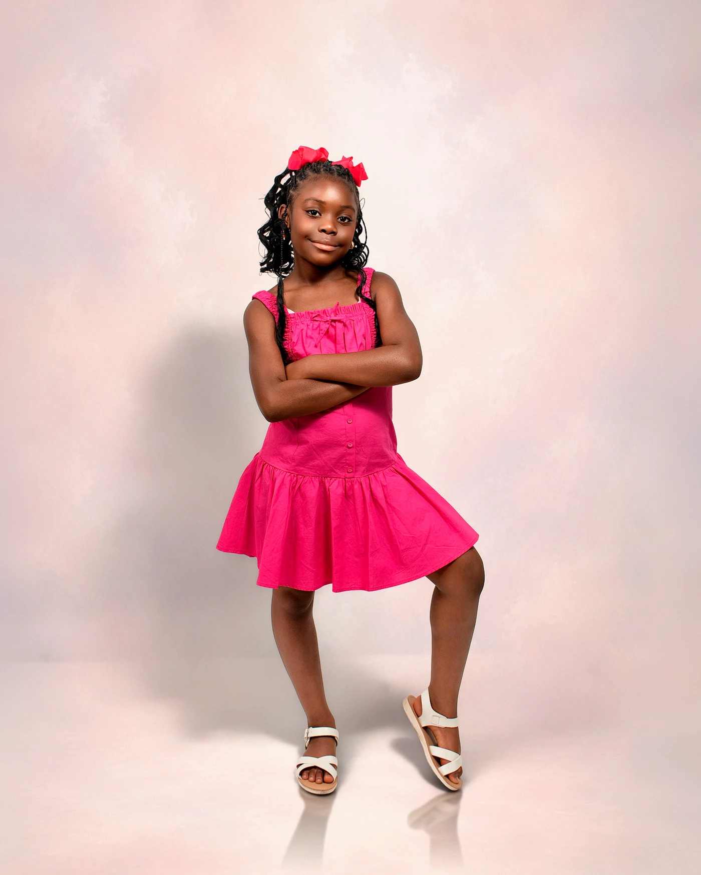 A child in a bright pink dress posing with folded arms