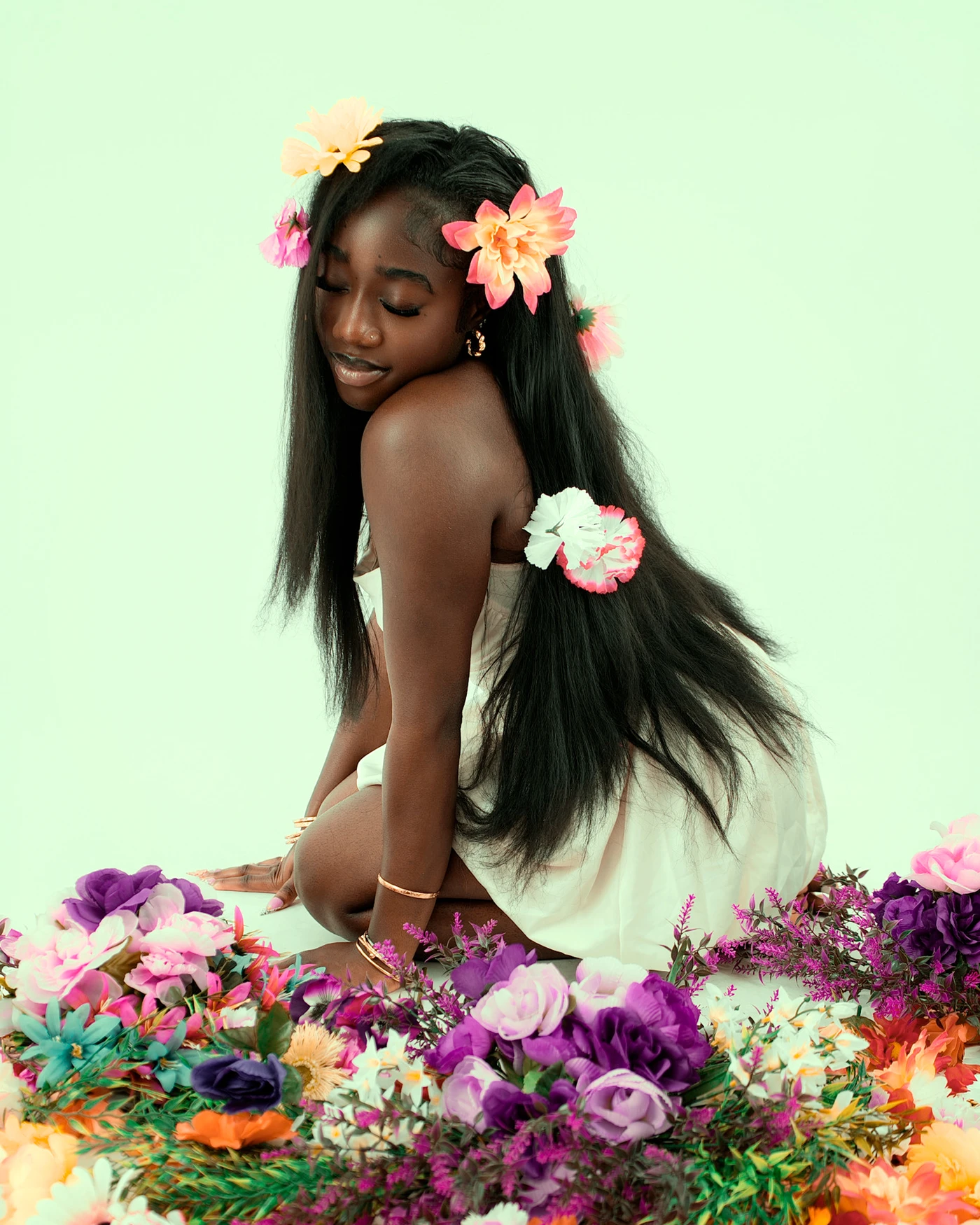 A portrait with flowers in long hair looking down over one shoulder