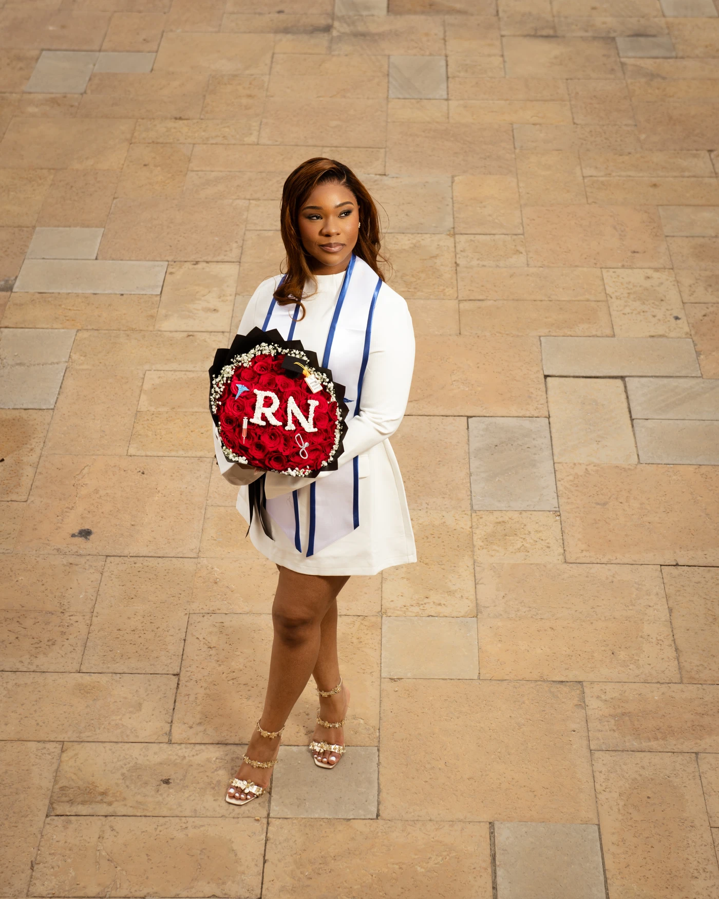 A nursing graduate holding a red rose bouquet with RN lettering