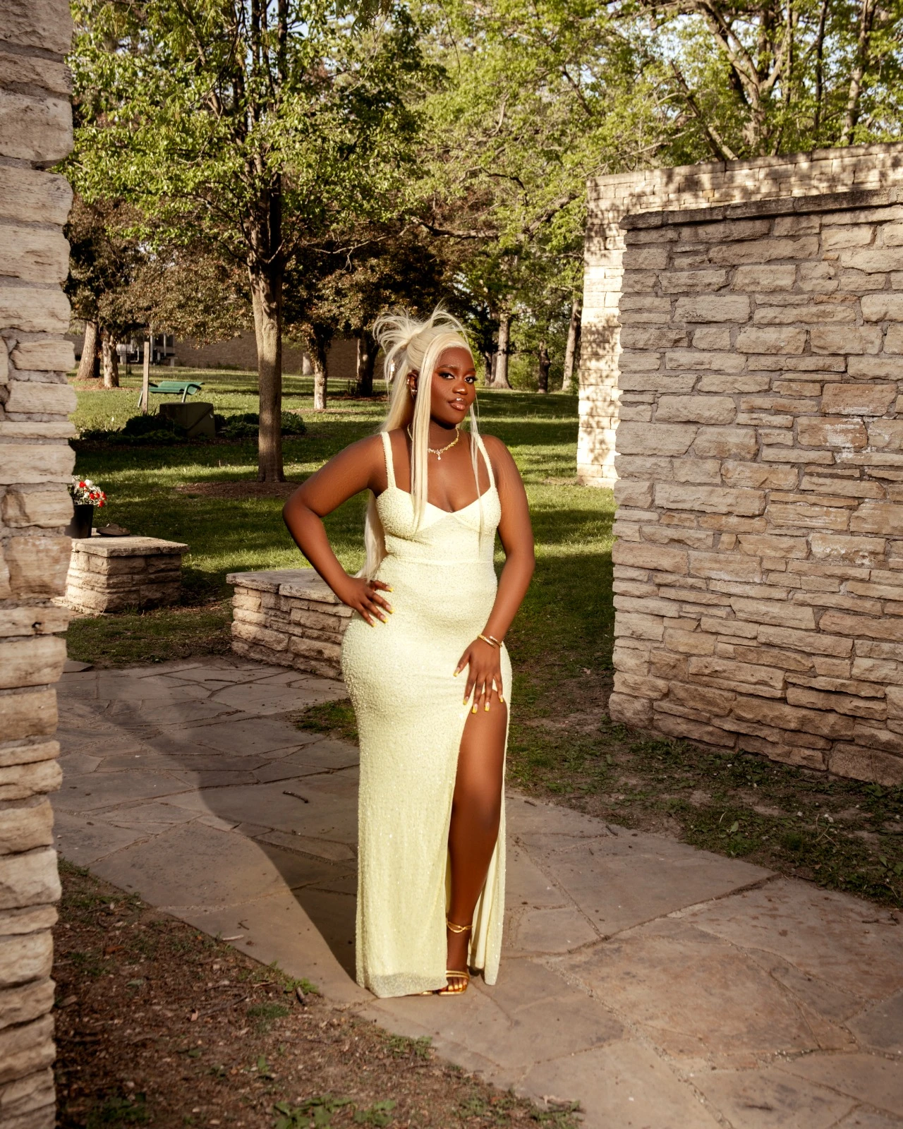 A full-length portrait in a yellow gown beside a stone wall