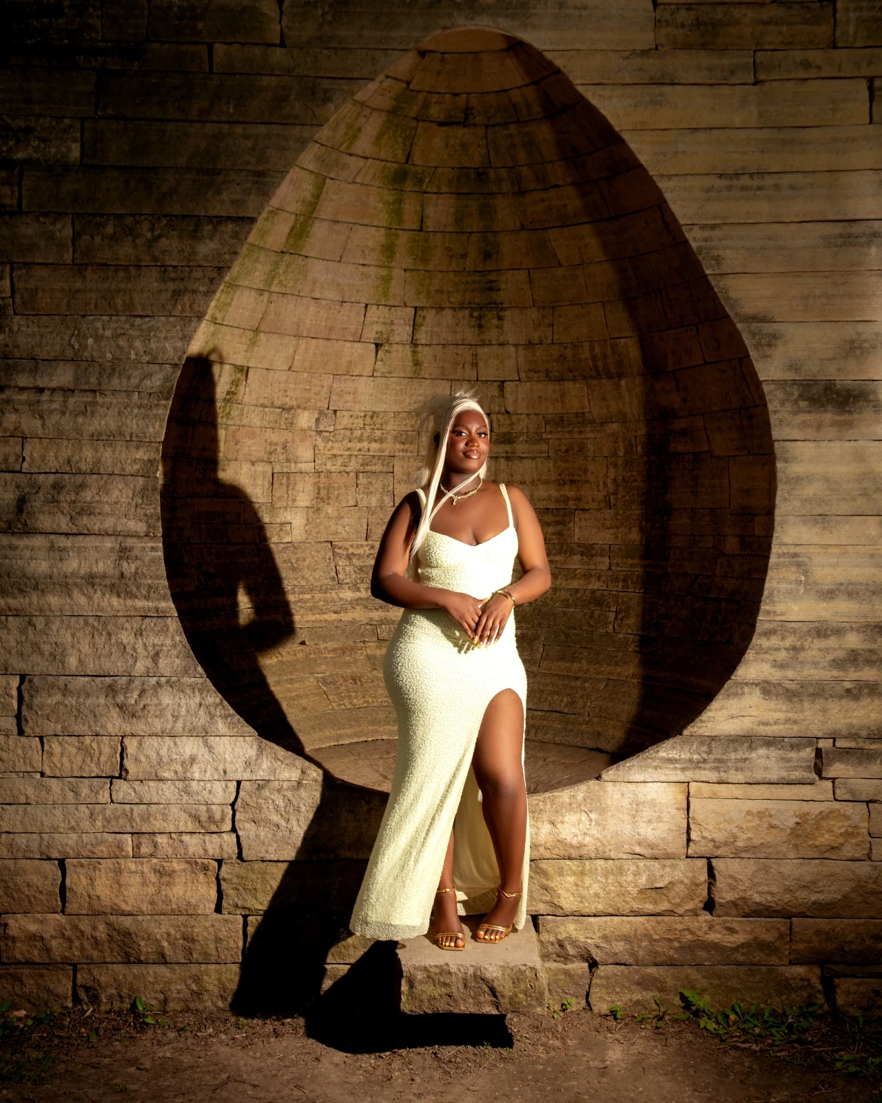 A portrait in a yellow gown framed by a curved stone alcove