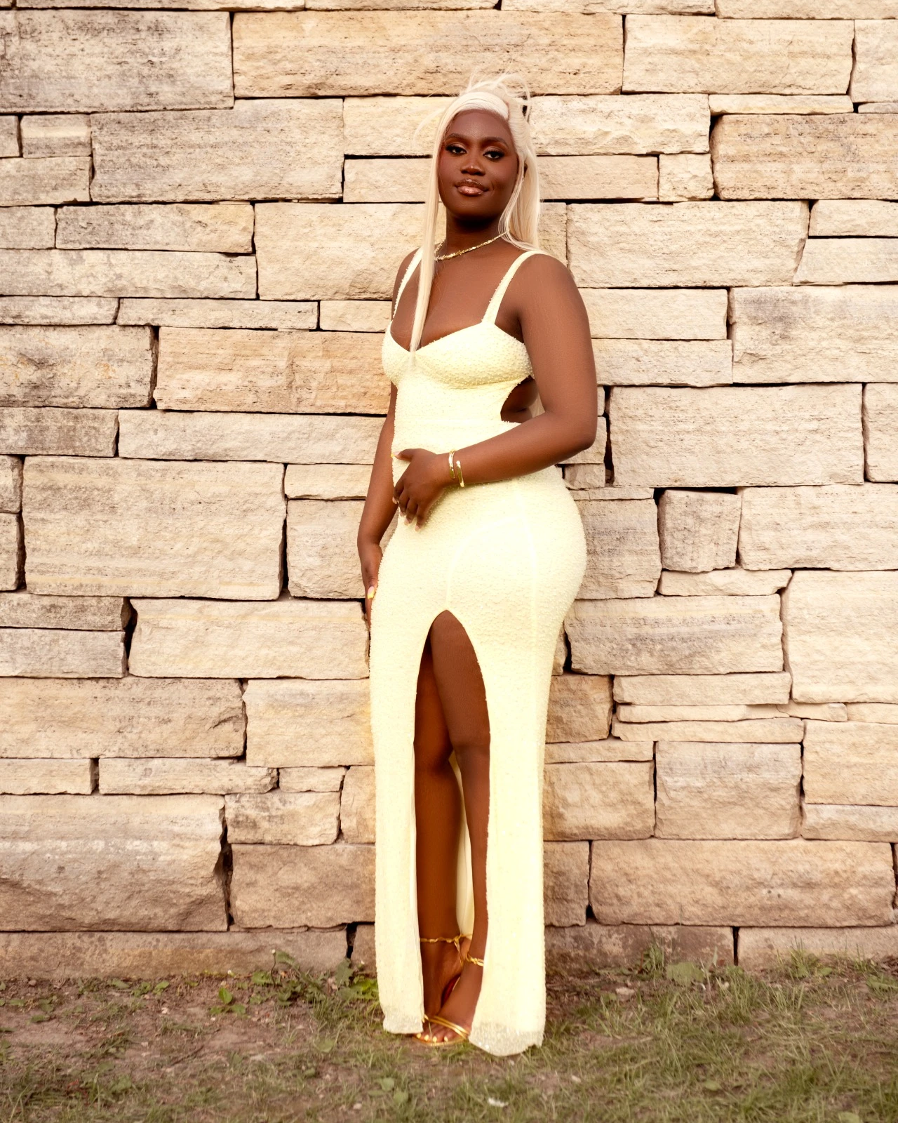 A portrait in a yellow gown against a textured stone wall