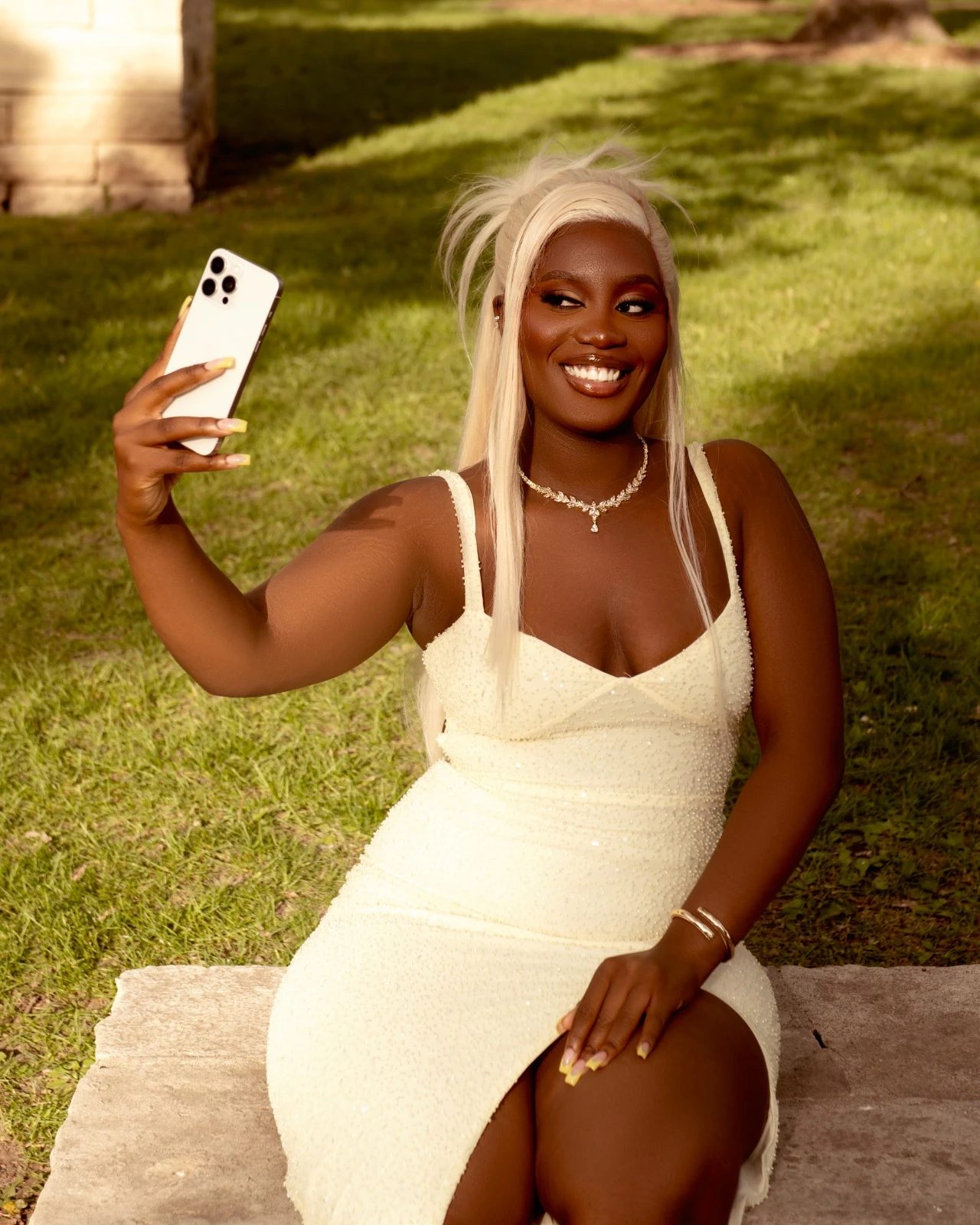 A playful outdoor portrait taking a selfie in a yellow gown