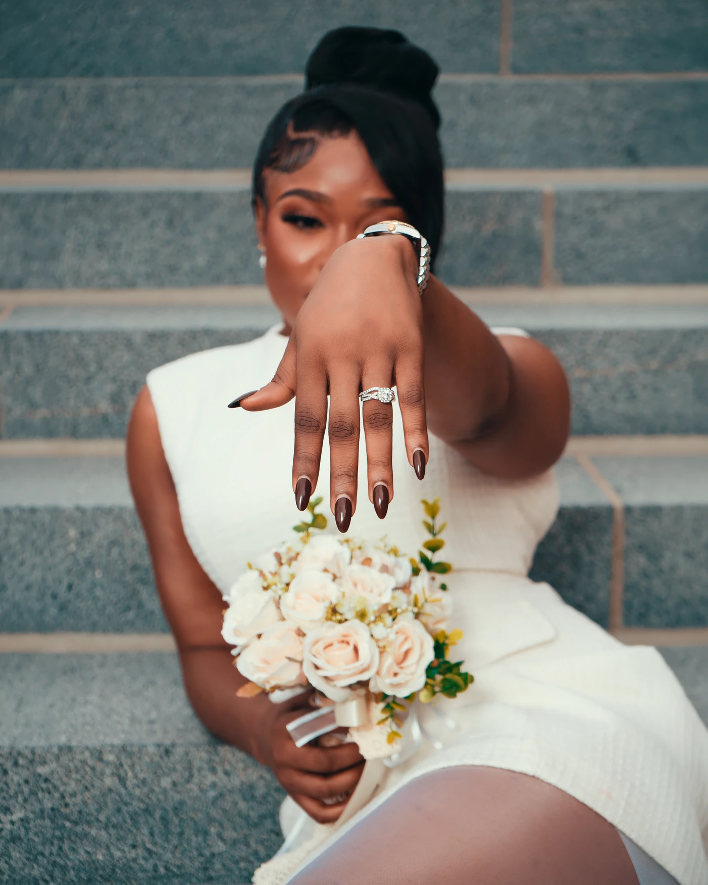 A bride showing her wedding ring while holding a bouquet